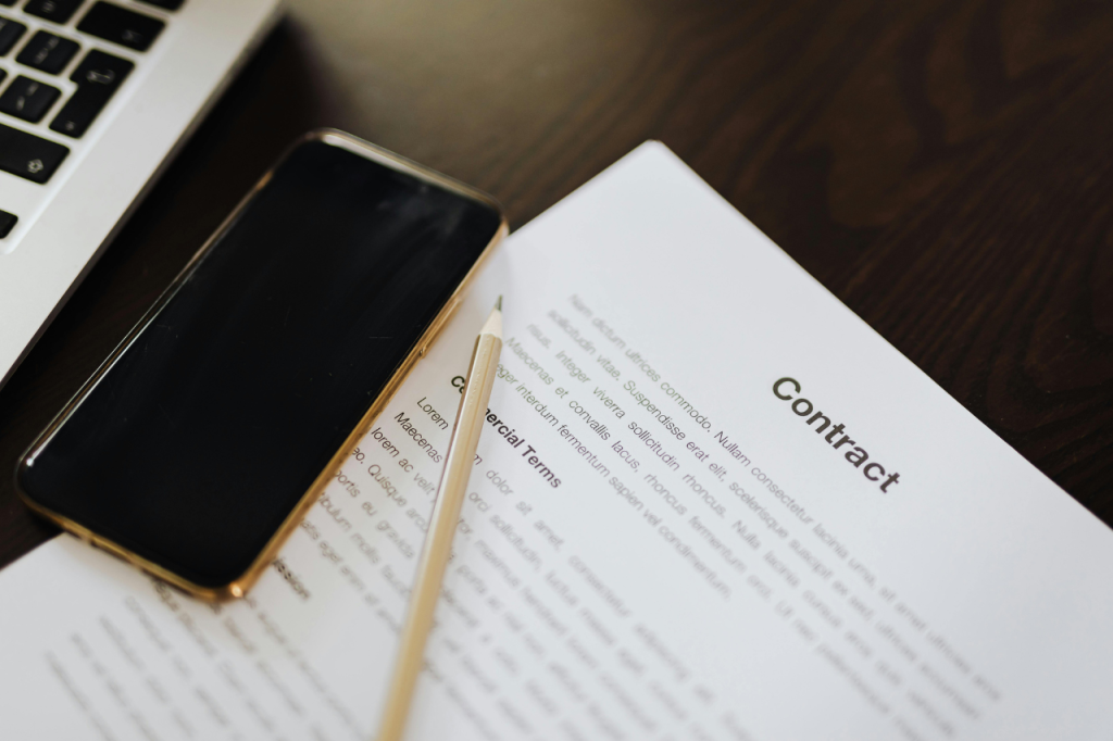 Profesjonalna umowa i smartfon na biurku, pokazujące dbałość o detale i spójność wizerunku marki.