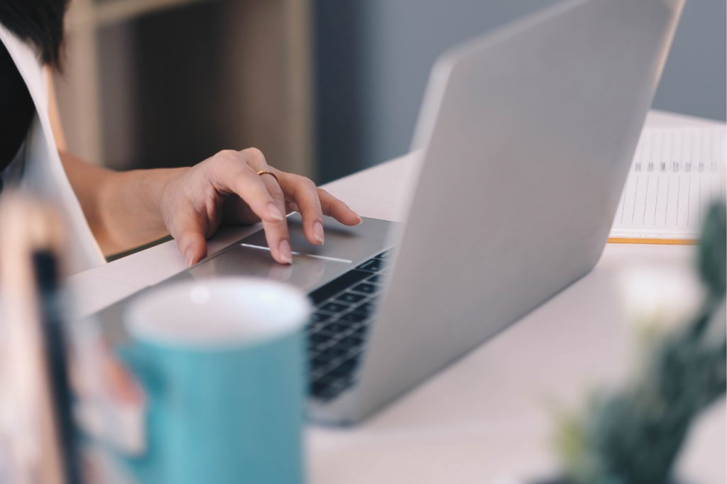 Kobieta pracuje przy laptopie z kawą i notatnikiem — porządek w dokumentach cyfrowych jako fundament sprawnego cyfrowego zaplecza marki