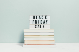 Tabliczka z napisem Black Friday Sale na stosie książek — jak ogarnąć więcej klientek bez chaosu